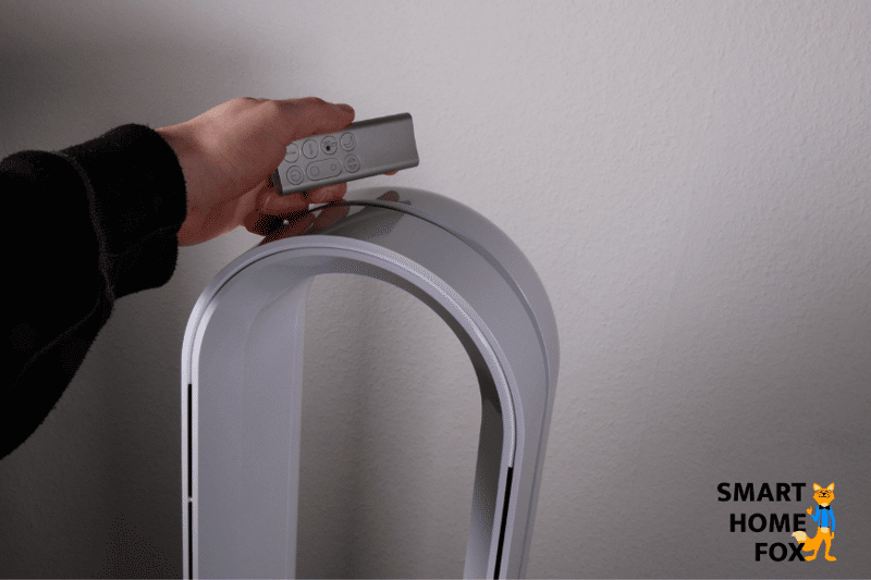 Die Fernbedienung wird mit der Hand, magnetisch am oberen Ende des Dyson Pure Cool TP04 Luftreiniger befestigt.